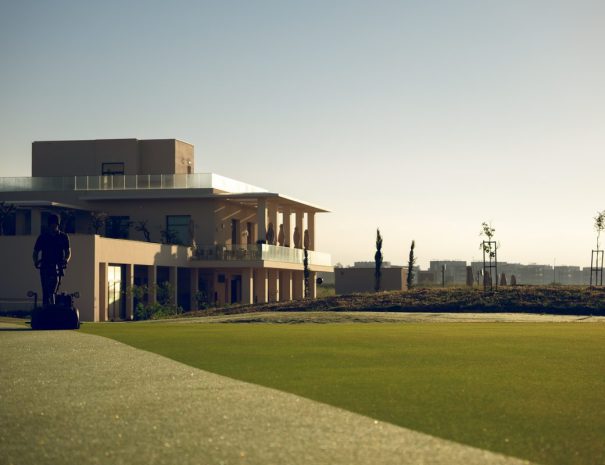 Greenkeeper mowing in front of the Limassol Greens clubhouse in the early morning light